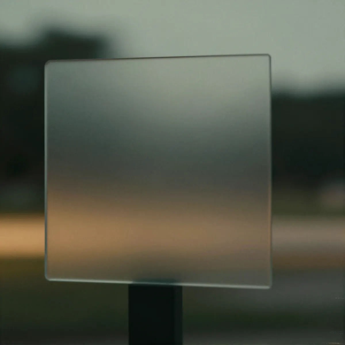 A frosted glass panel in front of a blurred green and amber dusk scene.